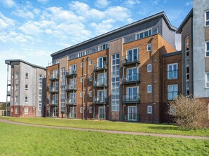 A multi-story residential building with balconies, brick facade, and a grassy courtyard. - 3 bedroom accommodation in Llanelli (Llanelli)
