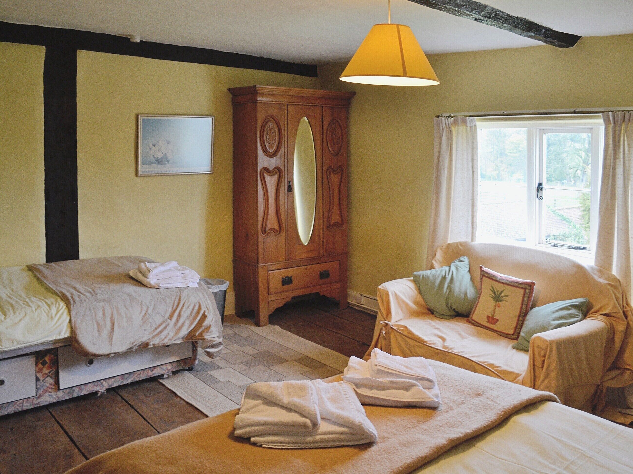 Un dormitorio con dos camas, un armario de madera, una ventana con cortinas y una lámpara colgante.