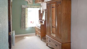 A room with a large wooden wardrobe, a mirror, and a ceiling fan. - 1 bedroom accommodation in Lowick Bridge (Lowick Bridge)