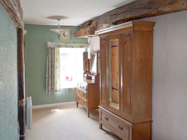 A room with a large wooden wardrobe, a mirror, and a ceiling fan. - 1 bedroom accommodation in Lowick Bridge (Lowick Bridge)