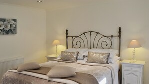 A neatly made bed with a decorative headboard, two bedside tables with lamps, and a wall-mounted artwork.