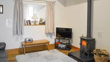 A cozy living room with a sofa, a TV, a wooden bench, a fireplace, and a bookshelf.