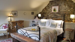 Ein Schlafzimmer mit Stehwand, einem Bett mit floraler Bettwäsche, einer Holzbank und einem Stuhl.