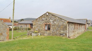 A stone building with a small window, surrounded by a grassy area and other stone buildings. - 3 bedroom accommodation in Brighstone (Brighstone)