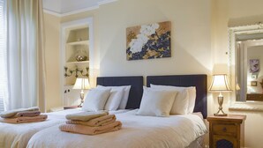 Un lit bien fait, avec des serviettes pliées, une table de chevet avec une lampe et un tableau accroché au mur.