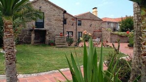 A stone building with a small garden in front. - Os Migueliños (Catoira)