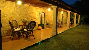 An outdoor patio with stone walls and a covered seating area. - Os Migueliños (Catoira)