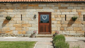 Un bâtiment en pierre avec un toit en tuiles, une porte en bois et des murs en pierre.
