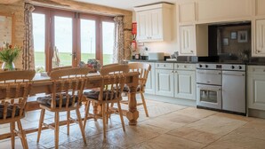 Une cuisine avec des chaises en bois, une table à manger, une cuisinière et des placards.