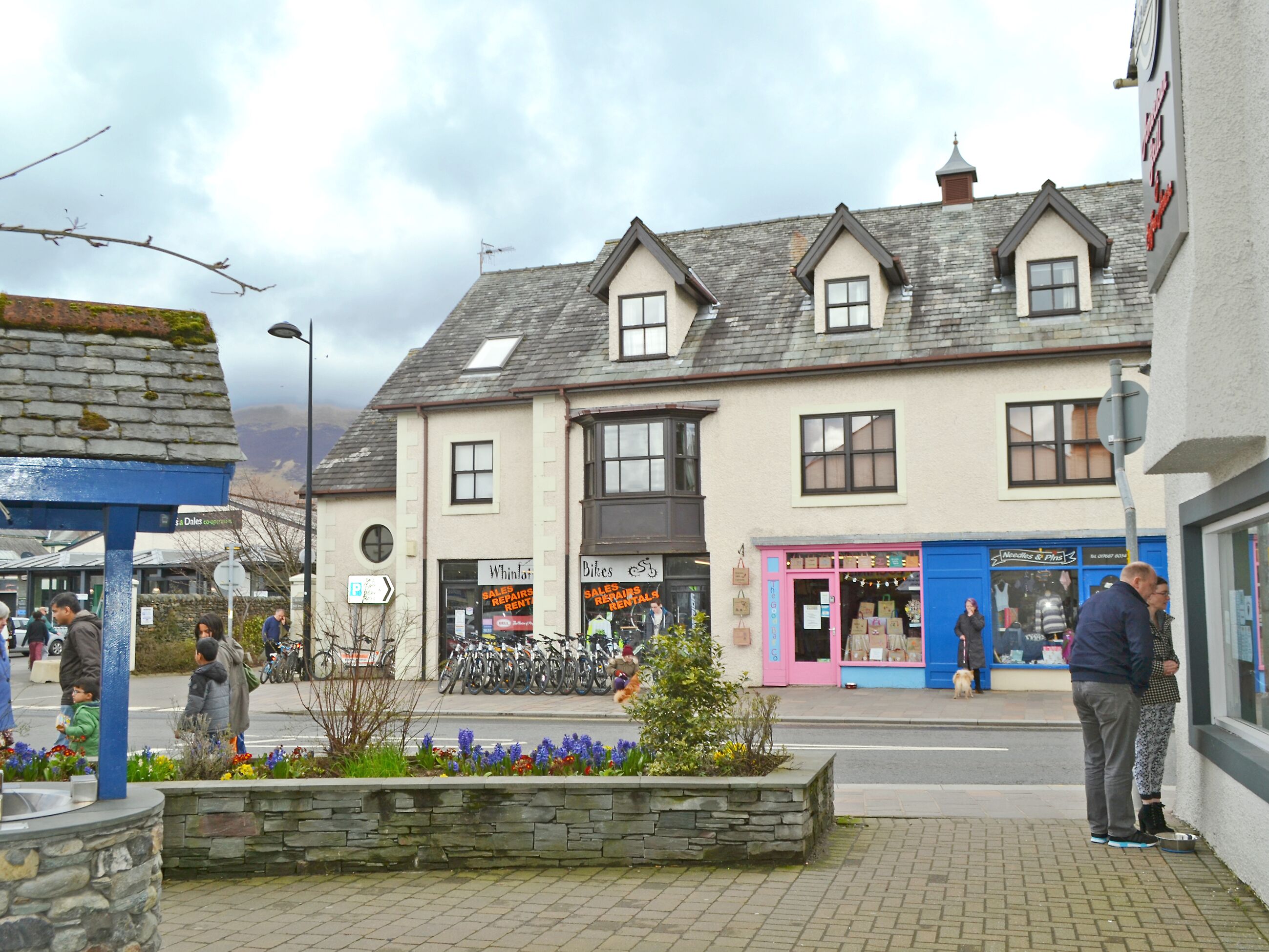 A street view with a row of shops, including a bike shop and a needle shop.