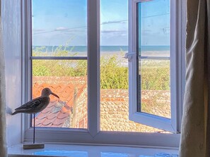 A bird perched on a window sill, with a view of a stone wall and greenery outside. - 2 bedroom accommodation in Bacton (Bacton)