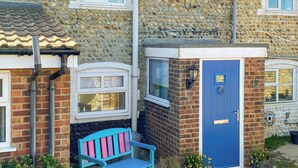 A stone house with a blue door, a bench, and a small garden area. - 2 bedroom accommodation in Bacton (Bacton)