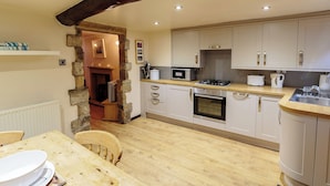 Een keuken met houten vloeren, een eettafel met stoelen, een stenen boog en moderne apparatuur.