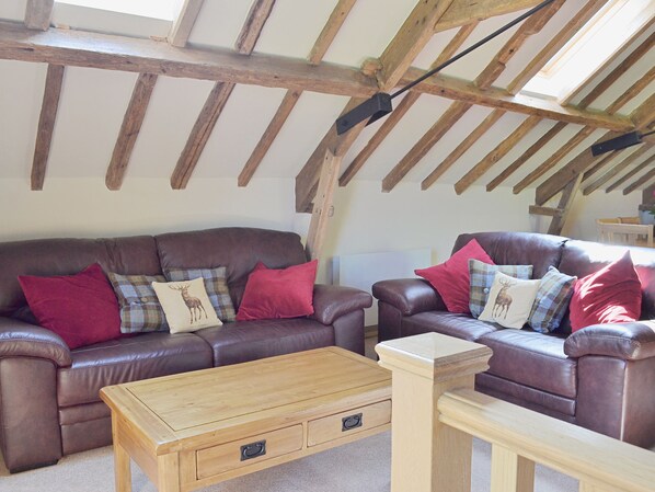 A cozy living room with two brown leather sofas, a wooden coffee table, and a wooden side table. - 2 bedroom accommodation in Aldbrough, near Hornsea (Aldbrough, near Hornsea)