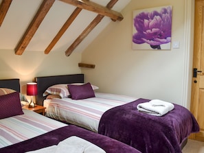 A bedroom with two beds, striped bedding, purple pillows, a red lamp, and a purple flower painting on the wall. - 2 bedroom accommodation in Aldbrough, near Hornsea (Aldbrough, near Hornsea)