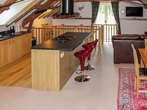A kitchen with wooden cabinets, a central island, and red bar stools. - 2 bedroom accommodation in Aldbrough, near Hornsea (Aldbrough, near Hornsea)