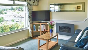 A living room with a sofa, a coffee table, a TV, a fireplace, and a bookshelf. - Badgers Rake 12 Squirrels Nest (Ambleside)