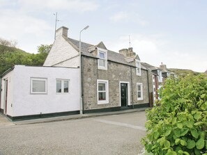 A stone building with a white facade, a door, and windows.