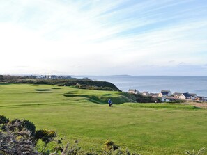 A golf course with a view of the sea and coastal buildings. - Boatmans Cottage - 27787 (Portessie, near Buckie)
