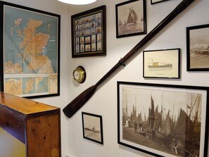 A wall with various maritime-themed artworks, a map, and a clock.