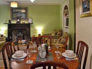 A dining room with a fireplace, a green wall, and a painting. - Boatmans Cottage - 27787 (Portessie, near Buckie)