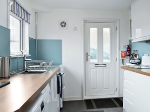 A compact kitchen with a sink, stove, and a door with frosted glass panels.