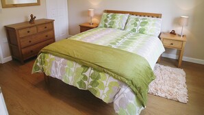 Une chambre à coucher comprenant un lit, deux tables de chevet, une commode, un miroir et un tapis.