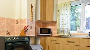 A kitchen with wooden cabinets, a microwave, and a trash bin.