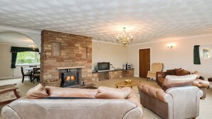 A living room with a stone fireplace, leather sofas, a television, and a chandelier.
