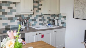 A kitchen with white cabinets, a tiled backsplash, and a wooden countertop.