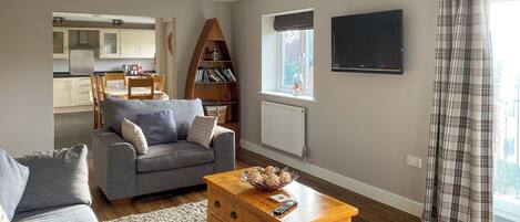 A living room with a grey sofa, wooden coffee table, and a bookshelf.