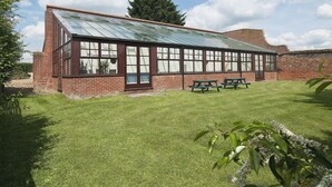 A brick building with large windows and a green roof, surrounded by a well-maintained lawn and picnic tables. - 4 bedroom accommodation in Necton, near Swaffham (Necton, near Swaffham)