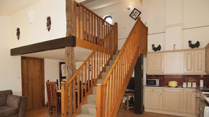 A spacious living area with a wooden staircase leading to a second floor, a kitchen with wooden cabinets, and a dining area with a table and chairs. - 4 bedroom accommodation in Necton, near Swaffham (Necton, near Swaffham)