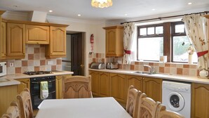 Cucina con mobili in legno, fornello, lavandino e tavolo da pranzo con sedie.