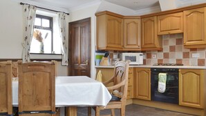 Una cucina con mobili in legno, un tavolo da pranzo con sedie, un forno a microonde e un fornello.