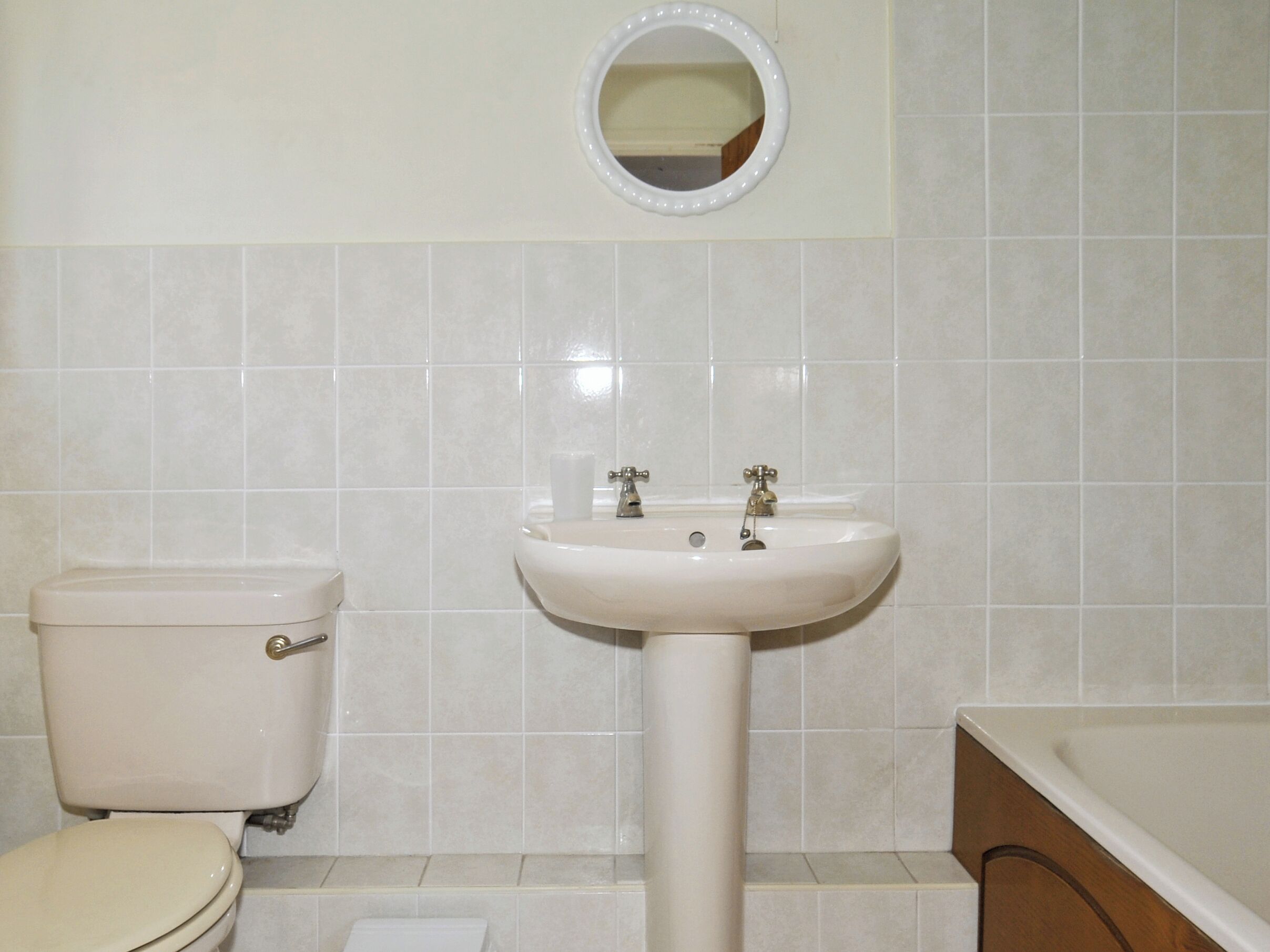 A bathroom with a toilet, sink, and mirror.
