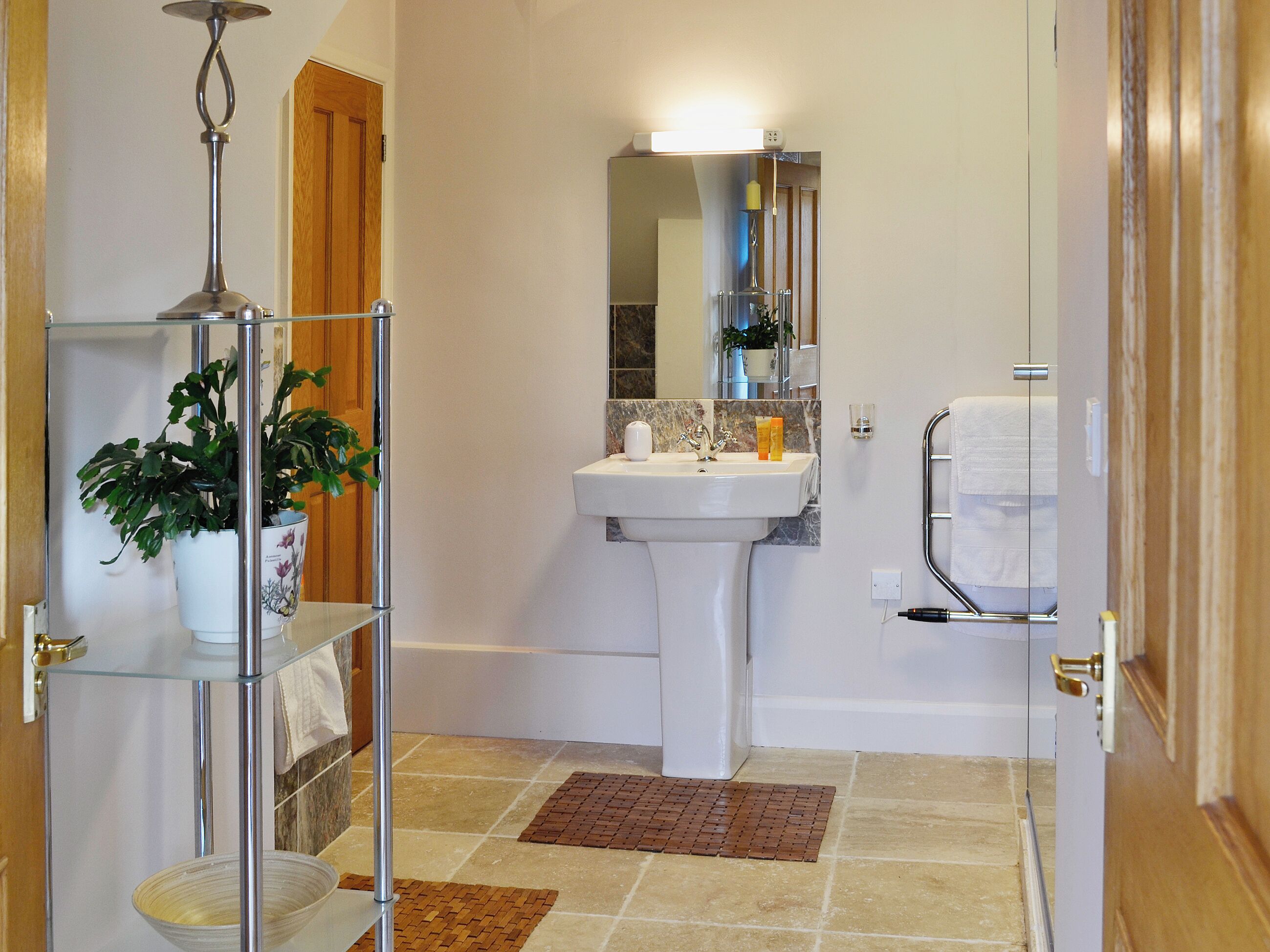 A bathroom with a sink, mirror, towel rack, and a plant on a shelf.