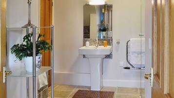 A bathroom with a sink, mirror, towel rack, and a plant on a shelf.