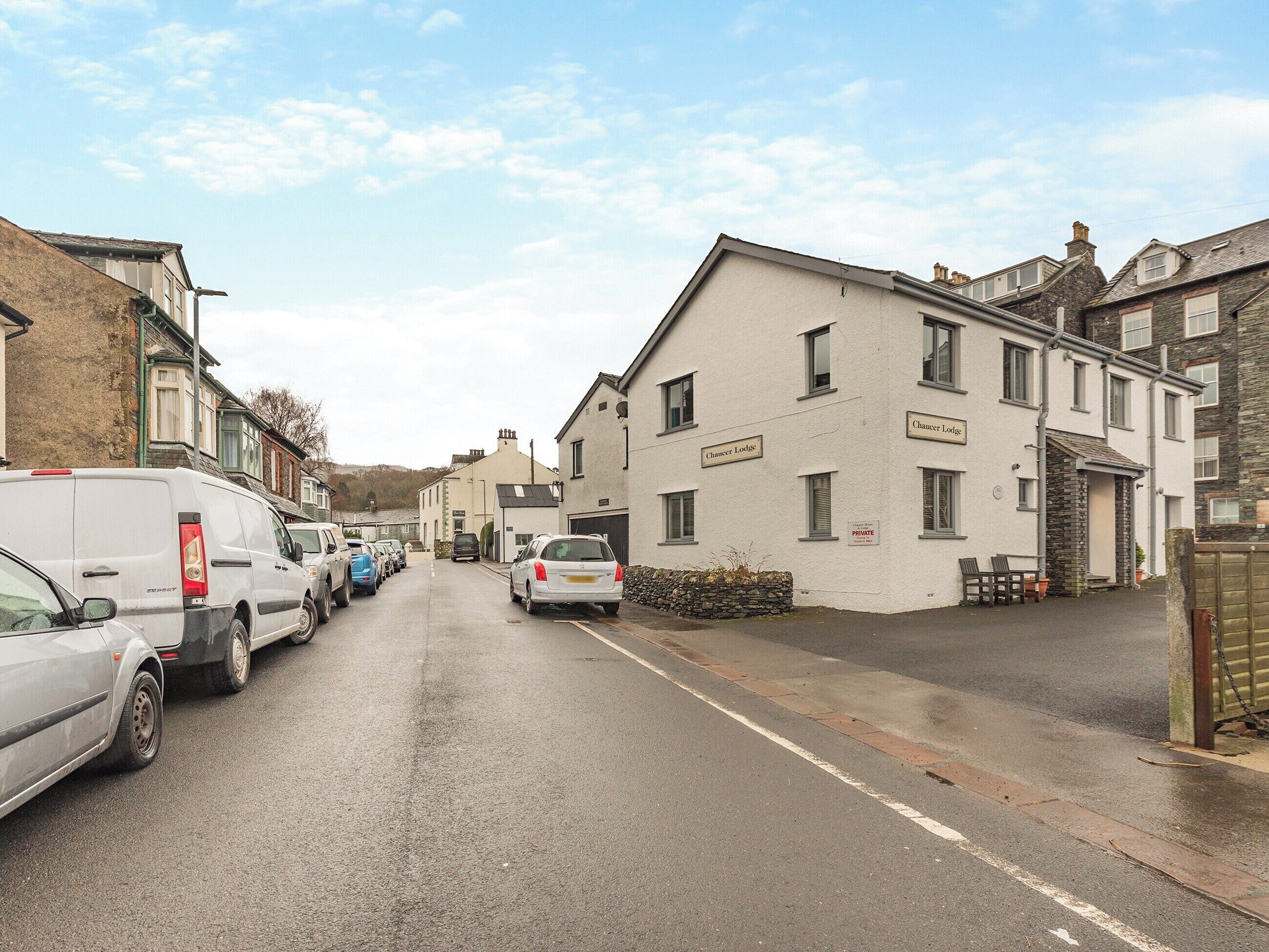 A street view with a row of parked cars and a building labeled "Chancer Lodge."