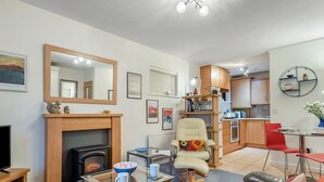 A modern living room with a fireplace, a dining area, and a kitchen. - Short breaks available all year. (Keswick)