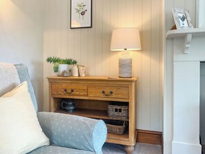 A cozy room with a wooden nightstand, a lamp, a framed picture, and a potted plant.