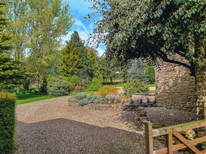 Un jardin avec un chemin de gravier, un mur de pierres et une clôture en bois.