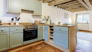 Une cuisine avec des meubles de couleur bleu clair, un plan de travail en bois et un sol en briques.