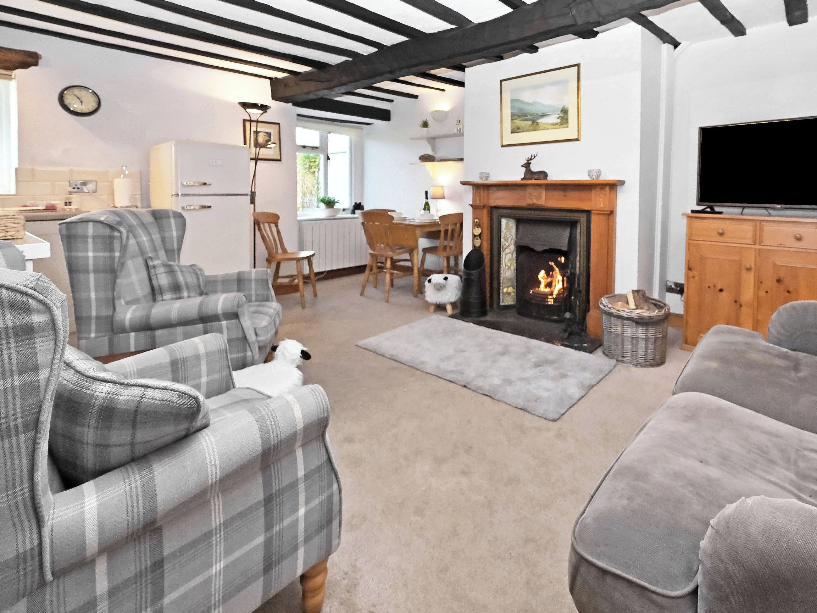 A living room with a fireplace, a television, and a dining area in the background.