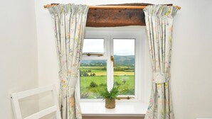 A bedroom with a window, a white bed, a white chair, and a view of a green landscape. - 2 bedroom accommodation in Bassenthwaite, near Keswick (Bassenthwaite, near Keswick)