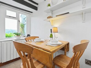 A dining area with a wooden table, four chairs, a bottle of wine, two glasses, and a lamp.