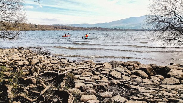 A rocky shoreline with kayakers on a calm lake, surrounded by trees and distant mountains. - 2 bedroom accommodation in Bassenthwaite, near Keswick (Bassenthwaite, near Keswick)