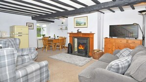 A cozy living room with a fireplace, a television, and a dining area with wooden furniture. - 2 bedroom accommodation in Bassenthwaite, near Keswick (Bassenthwaite, near Keswick)
