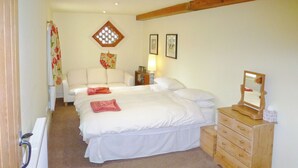 A bedroom with a double bed, a wooden dresser, a radiator, a window with a floral curtain, and a wooden ceiling beam. - 2 bedroom accommodation in Gringley-on-the-Hill (Gringley-on-the-Hill)