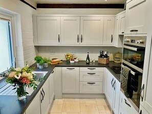 A modern kitchen with white cabinets, a black countertop, and a built-in oven.